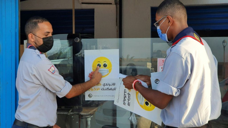 Libyan medical workers stick informative smilies on a shop window for a Covid-19 awareness campaign at the busy Friday market in the capital Tripoli