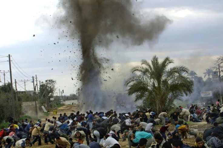In this photo taken on March 7, 2004, Palestinians run to take cover during clashes with Israeli forces in the Nuseirat refugee camp in the Gaza Strip