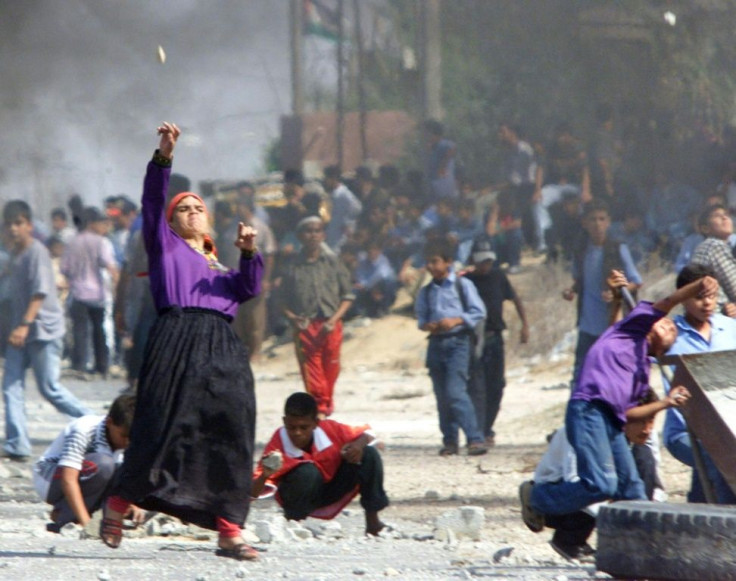 In this file photo taken in October 2000, a Palestinian woman throw stones at Israeli troops during clashes in the Gaza Strip
