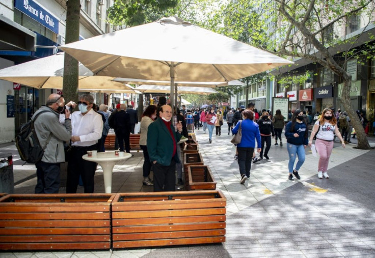 People walk along a pedestrian street past an open bar in downtown Santiago