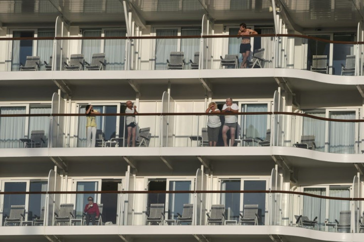 Passangers look out from their balconies aboard the Maltese-flagged Mein Schiff 6, operated by German travel giant TUI, at the port of Piraeus