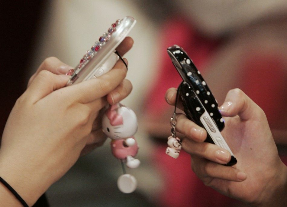 Middle-school girls use mobile phones as they chat in a restaurant in Seoul.