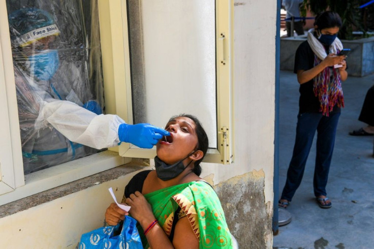 A medical worker collects a swab sample from a woman for a coronavirus test in New Delhi