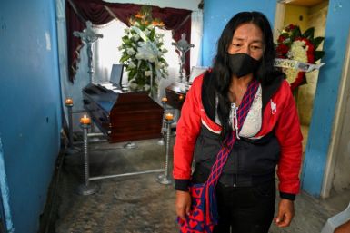Lucila Huila stands beside the coffins of her two sons, who were among six men shot dead by unidentified gunmen in Colombia's Cauca department in August 2020