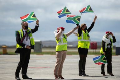 Ground crew wave flags as an Emirates airliner lands in Cape Town from Dubai, marking the end of South Africa's long ban on international flights