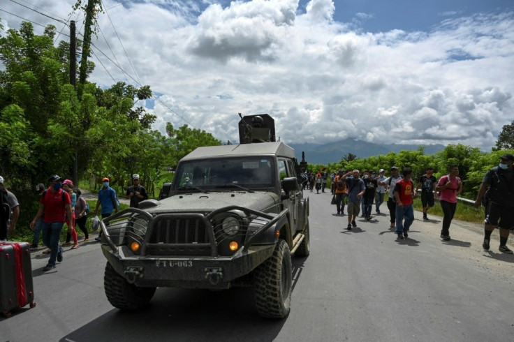 Honduran migrants, part of a caravan heading to the US, walk alongside an army truck in Entre Rios, Guatemala, after crossing the border on October 1, 2020