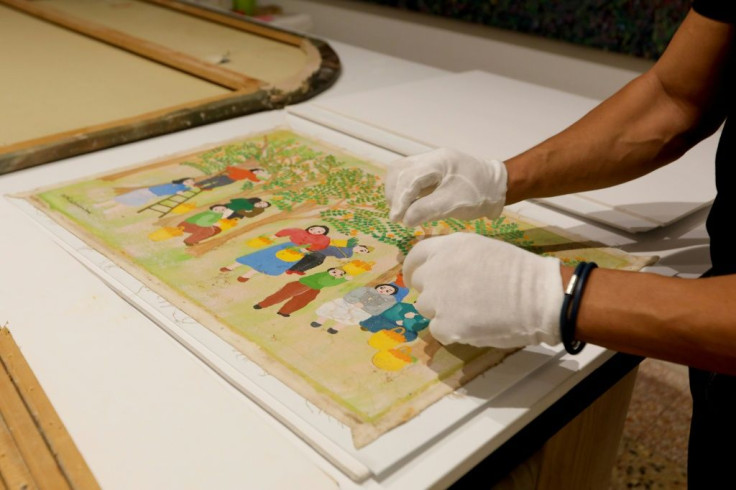 Gaby Maamary, a Lebanese artwork conservation specialist, examines a damaged painting by late artist Sophie Yeramian