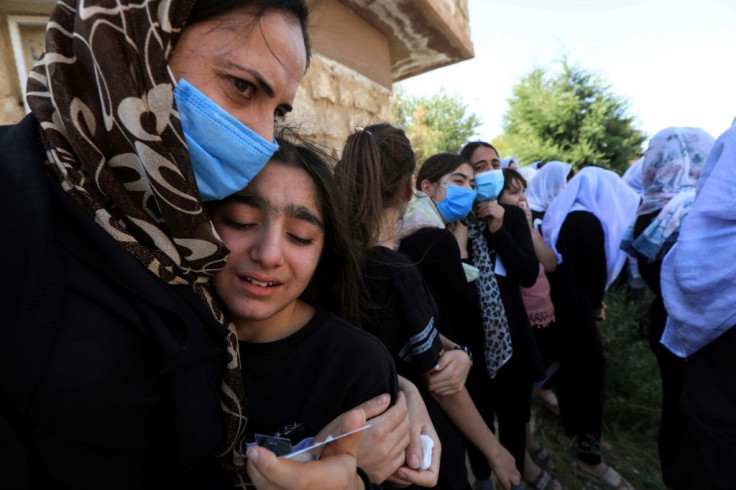 An Iraqi Yazidi woman comforts a grieving youngster at the funeral of Baba Sheikh Khurto Hajji Ismail, hailed as a "beacon of light" for his compassion towards the survivors of jihadist forced marriages and other atrocities