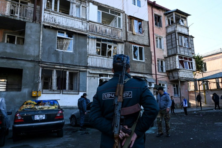 A police officer stands in front of an apartment building that was supposedly damaged by recent shelling