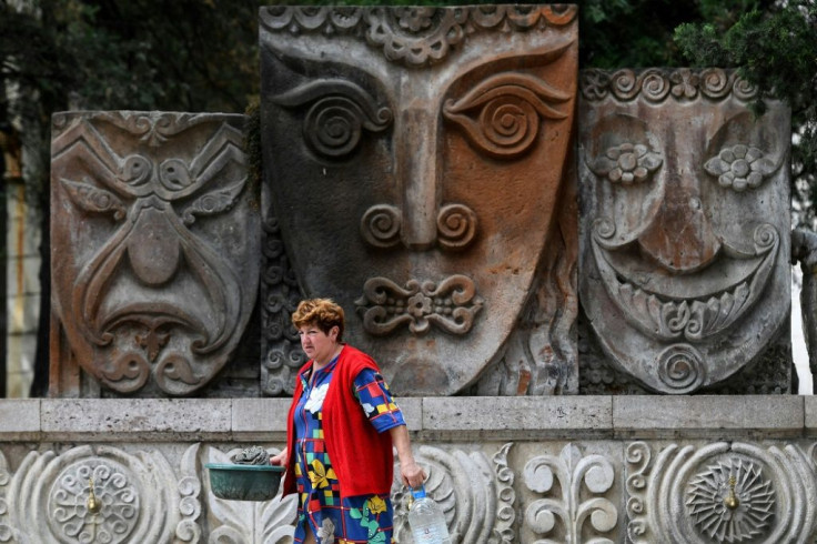 A woman collects drinking water from a spring on a street