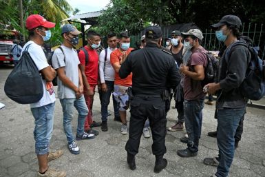 A policeman speaks with Honduran migrants, part of a US-bound caravan, outside a migrant shelter in the municipality of San Marcos, Guatemala, on October 3, 2020