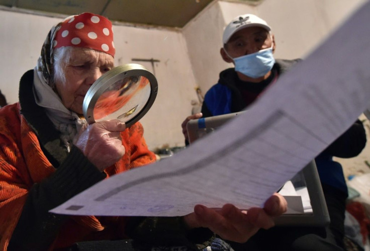 An elderly woman looks through her ballot paper during early voting for Kyrgyzstan's parliamentary election