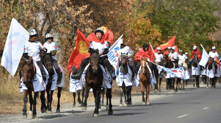 Supporters of the Birimdik (Unity) pro-government party wearing national 'Ak-kalpak' hats with flags ride horses on a road during a campaign event in the village of Koy-Tash, some 20 kms from the capital Bishkek