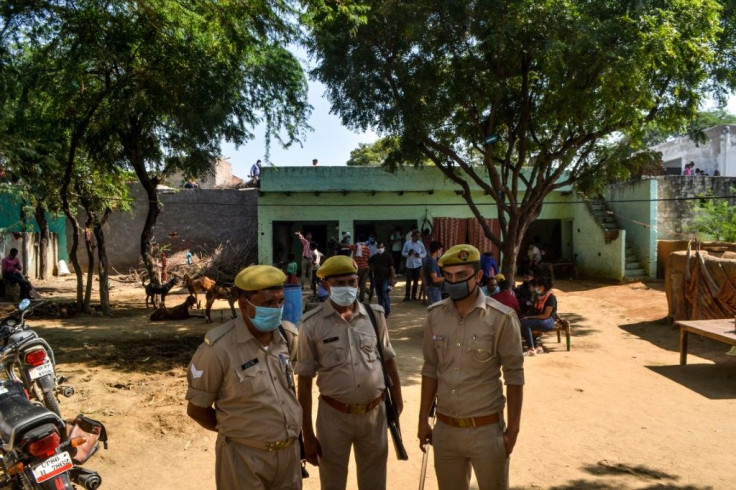 Police personnel stand guard in the village of a 19-year-old woman allegedly gang-raped and killed by four men in Bool Garhi, Uttar Pradesh state