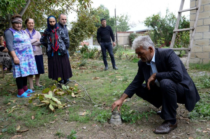 Locals gather near the remains of a shell in the Azerbaijani town of Beylagan on Sunday during the fighting between Armenia and Azerbaijan over the breakaway Nagorno-Karabakh region.