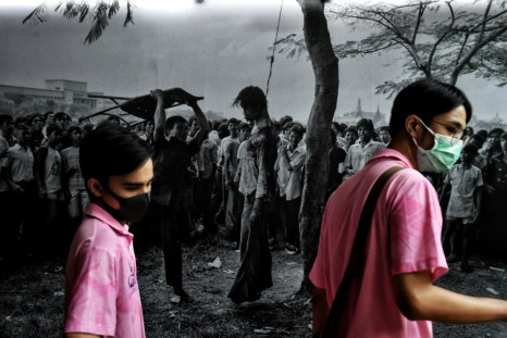 Students walk past US photojournalist Neal Ulevichâs image of a lynched protester during the Thammasat University massacre in October 1976 at an exhibition commemorating the event at Thammasat University in Bangkok