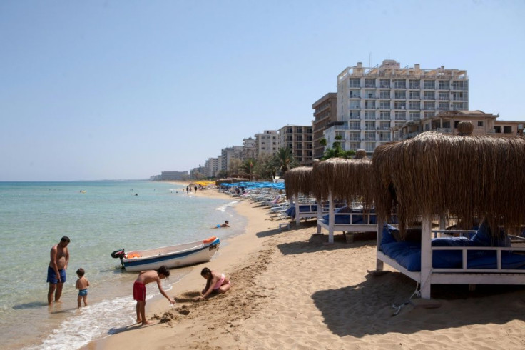 Tourists on a beach near the fenced-off beach area of the Turkish military-controlled ghost town of Varosha in northern Cyprus