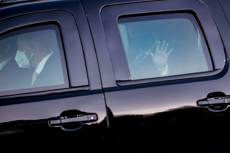 President Donald Trump waves from his car with masked members of the US Secret Service at Walter Reed Medical Center