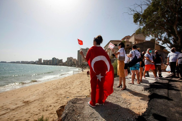 A woman holds the flags of Turkey and of the self-proclaimed Turkish Republic of Northern Cyprus in Varosha in the Turkish-occupied north of the divided eastern Mediterranean island of Cyprus
