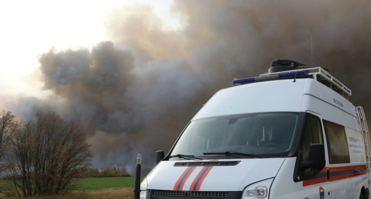 This handout picture taken and released by the Russian Emergencies Ministry on October 8, 2020 shows smoke rising from a fire at a munitions depot as an emergency car is seen on a road in the Ryazan region