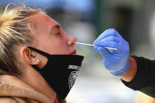 A medical worker takes a nasal swab sample from a student to test for COVID-19 in New York City.