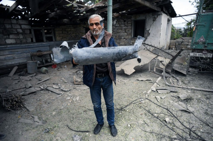 A man shows off a shell fragment in the yard of his brother's house which was hit by the bombardment