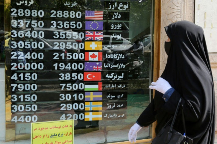 An Iranian woman checks a display board at a currency exchange shop in Tehran in September 2020 as US sanctions wreak havoc on the economy