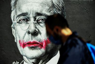 A man walks past a mural with an image of former Colombian President (2002-2010) Alvaro Uribe, in Bogota on August 21, 2020