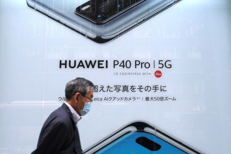 This picture taken on June 27, 2020 shows a man in Tokyo passing an advertisement for Huawei's 5G-capable smartphone; Apple is expected to unveil its own as it seeks to maintain its premium image
