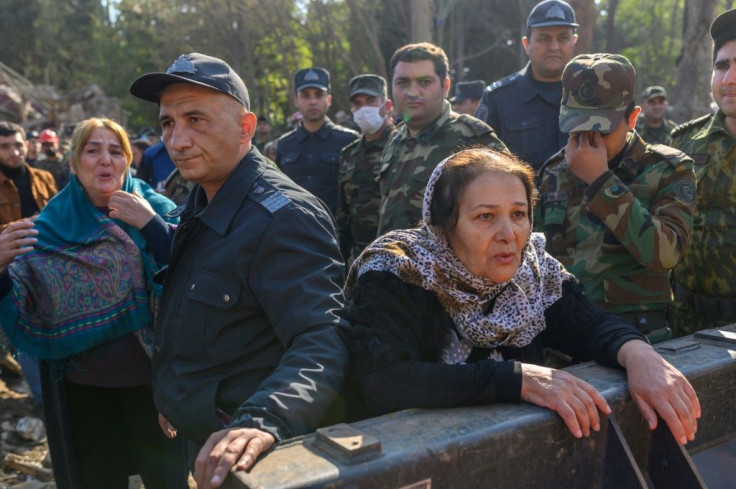 People gather at the blast site hit by a rocket