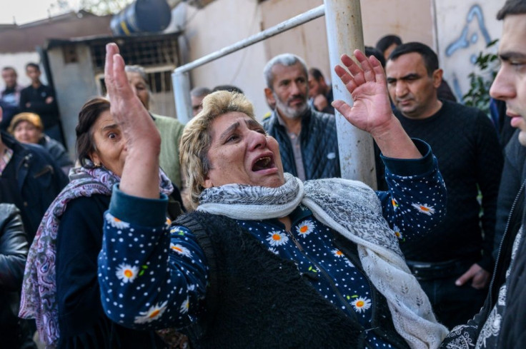 Women react as rescuers search for victims or survivors at a blast site