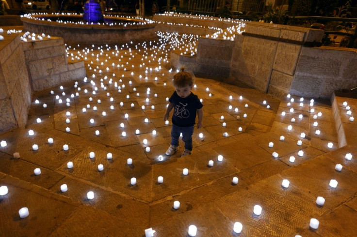 A child walks amid  candles placed by Israeli anti-government activists to honour victims of the coronavirus pandemic in Jerusalem