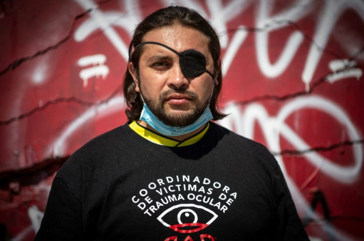 Felipe Riquelme, 41, stands in front of a defaced monument to the Chilean police, the spot where he was hit by a tear gas canister that left him blind in one eye, as he participated in social protests last year