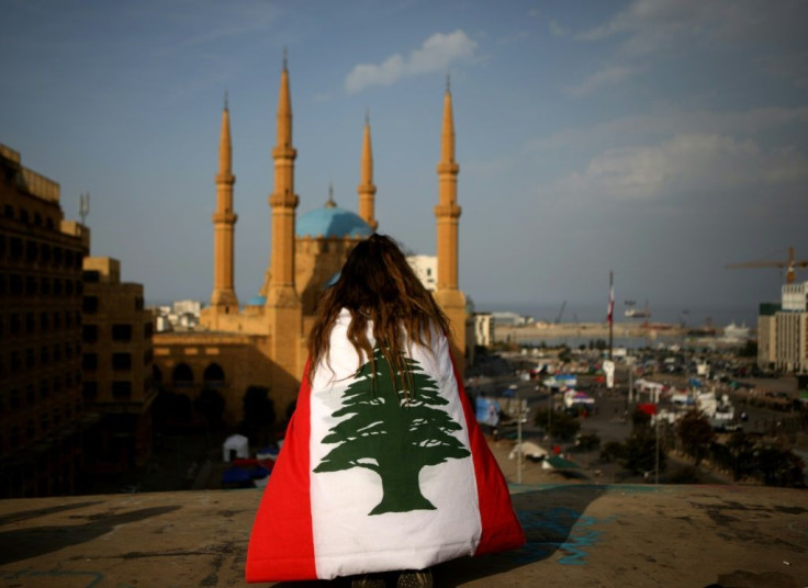 A Lebanese anti-government protester draped in a national flag sits on a rooftop overlooking Mohammed al-Amin mosque and Martyrs Square in downtown Beirut