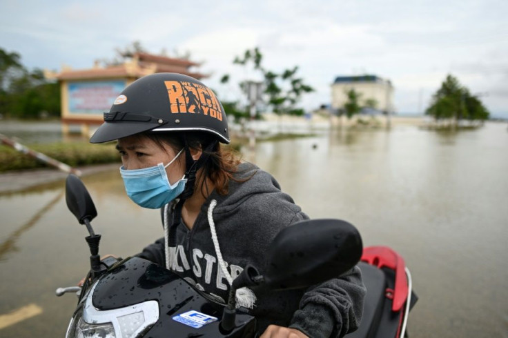 A woman pushes her scooter along a flooded road in Quang Dien district in central Vietnam's Hue province