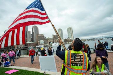 A man in a QAnon vest waves a US flag as demonstrators gather on October 5, 2020 to protest mandatory flu vaccines for children in Boston, Massachusetts