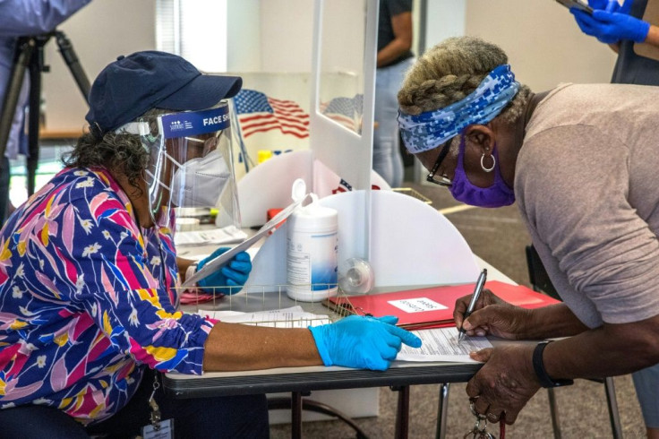 A poll worker (L) assists a voter at the Mecklenburg County library in Charlotte, North Carolina