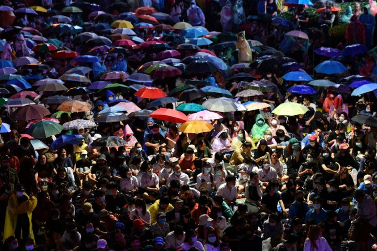 Pro-democracy protesters use umbrellas to shelter from the rain during an anti-government rally in Bangkok