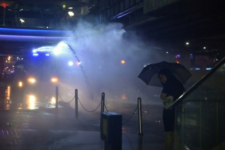 A pro-democracy protester uses an umbrella to shield from a police water cannon in Bangkok