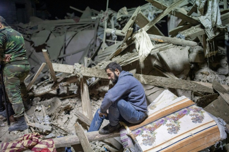 A resident of the city of Ganja, Azerbaijan, sits amid the rubble and awaits the search for his relatives as rescue teams work at a site hit by a rocket during fighting over the breakaway region of Nagorno-Karabakh