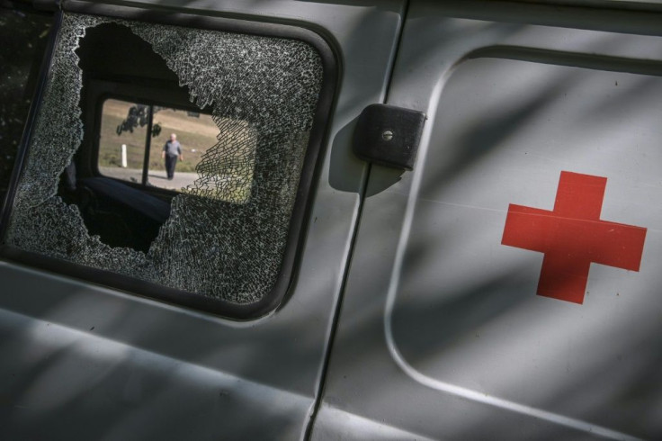 Ambulances and military vehicles move at speed down the road near the frontline