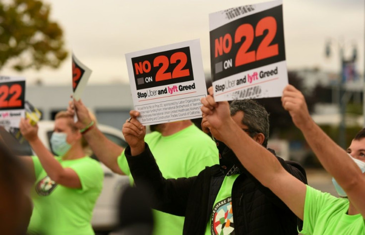 Rideshare drivers hold signs supporting a "No" vote on Proposition 22 in Oakland, California on October 09, 2020