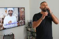Israeli singer Elkana Marziano, 28, sings along with a video clip of his collaboration with Emirati artist Walid Aljasim (image on screen)