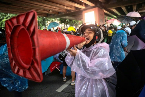 A Thai protester jokingly uses a traffic cone as a loudhailer during a rally at Victory Monument in Bangkok. The protestors are calling for the resignation of the prime minister and reforms to the monarchy