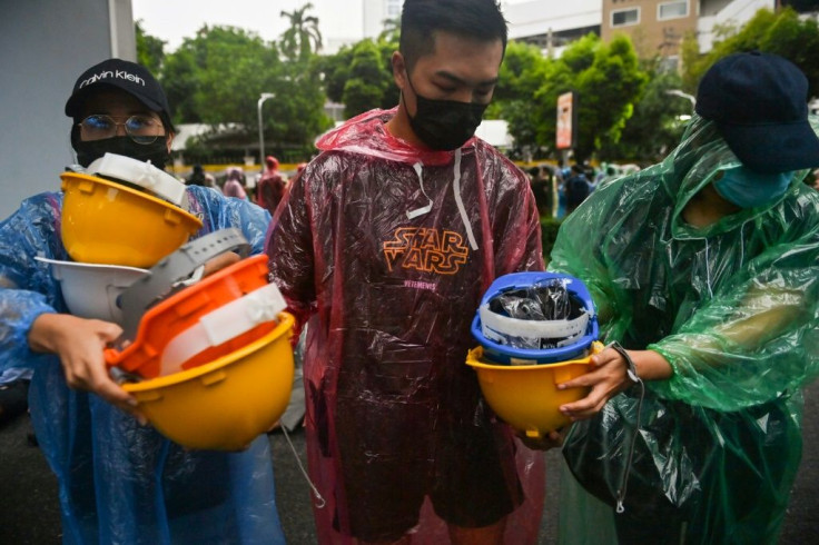 Protesters hand out hard hats during an anti-government rally at Victory Monument in Bangkok