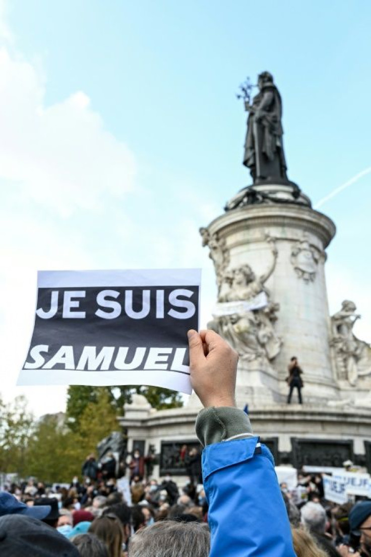 A person holds a placard reading "I am Samuel" as people gather on Place de la Republique in Paris on October 18, 2020, in homage to history teacher Samuel Paty two days after he was beheaded by an attacker who was shot dead by policemen.Thousands of peop