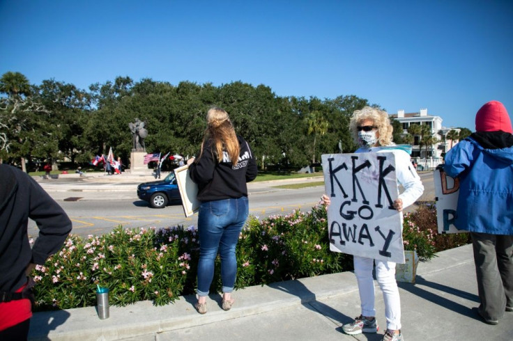 Several anti-racist protestors hold signs and chant slogans at pro-Confederate flaggers across the street in a park in downtown Charleston, South Carolina