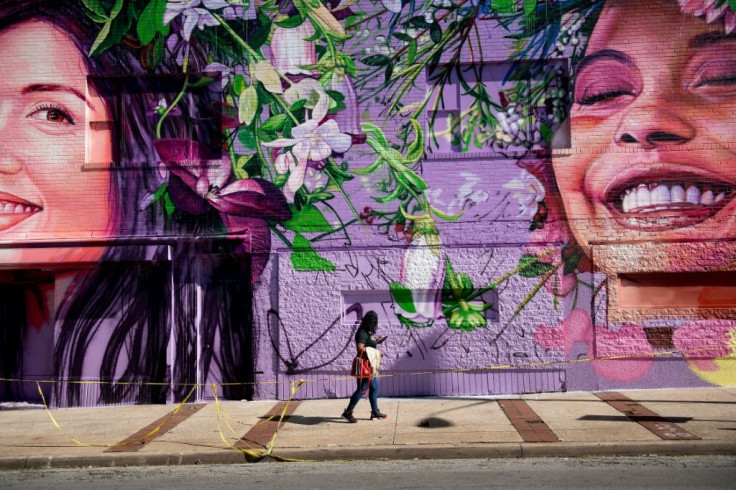 A woman walks past a mural in Baltimore's Charles Village neighborhood