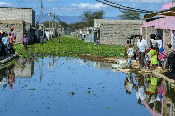 Residents of Kihoto estate on the shores of Lake Naivasha stand on elevated pavements outside their homes after the lake inundated buildings and infrastructure