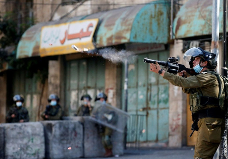 A member of Israeli security forces fires tear gas to disperse Palestinian protesters amid clashes in the occupied West Bank town of Hebron, on September 25